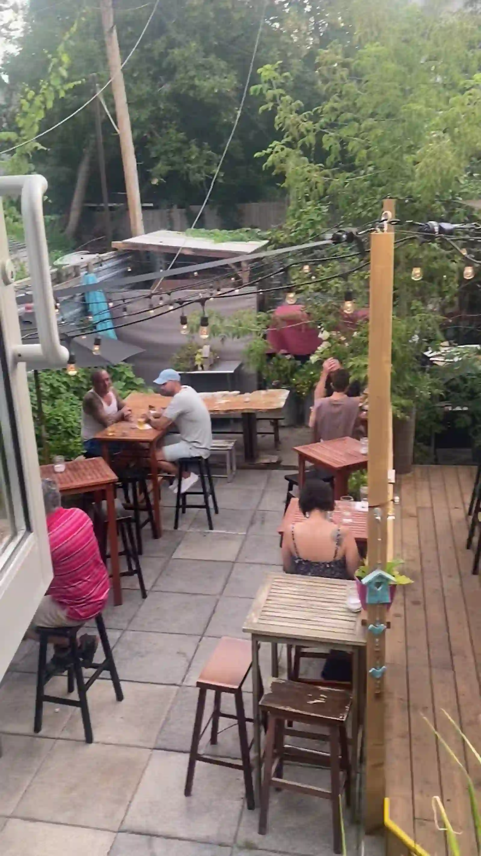 Back patio with string lights, wooden tables and greenery
